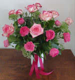 Bouquet of pink roses with a pink ribbon i a white vase